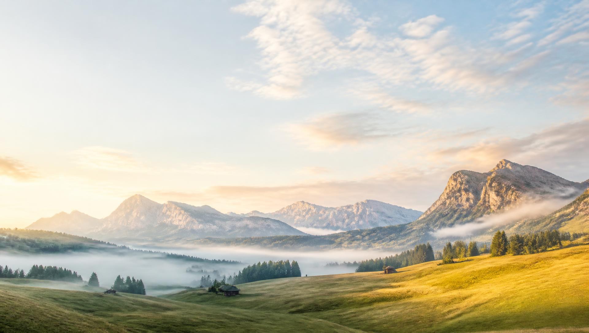 Weites Alpental im Morgenlicht mit Nebel über dem Tal